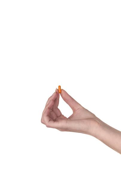 Hand holding an orange capsule isolated on white background - Foto, immagini