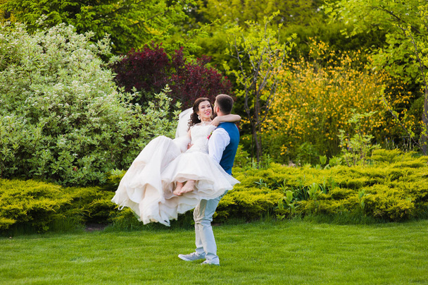 Verliebter Bräutigam wirbelt seine lächelnde Barfußbraut durcheinander - Foto, Bild
