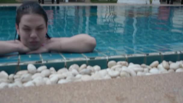 Brunette girl swims in the pool - Imágenes, Vídeo