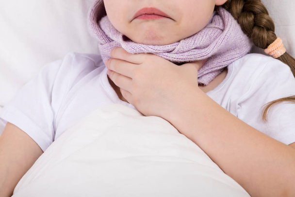 in the bed the girl has a sore throat wrapped in a scarf - Foto, Imagen