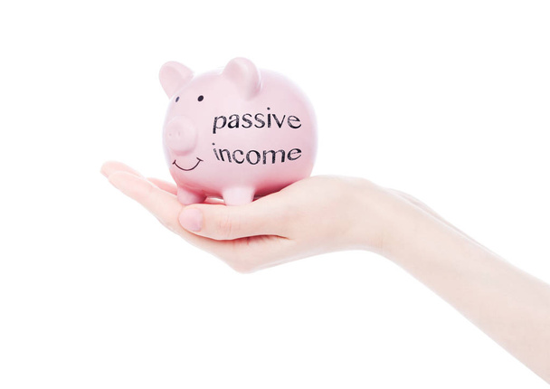 Female hand holds piggy bank passive income text - Photo, Image