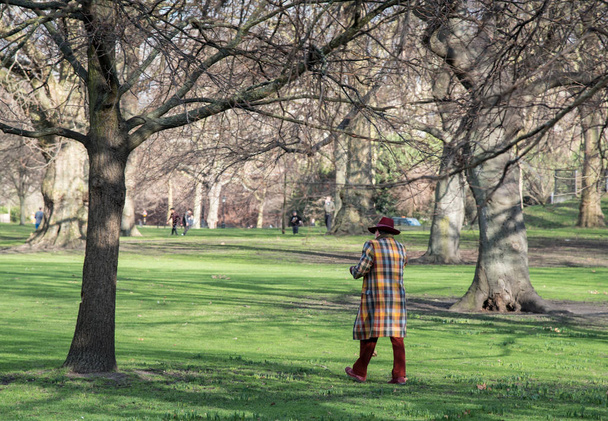 Man gekleed in kleurrijke kostuum wandelen in het park - Foto, afbeelding