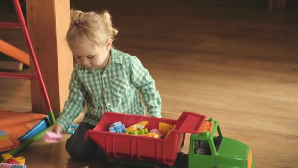 Мальчик кладет игрушки в багажник большого грузовика. Играть и порядок в детской комнате. Симпатичный умный мальчик, играющий с игрушечными машинами. Разработка и бесплатная игра. Детский сад или уютный семейный дом. Мальчик со стильной прической
 - Кадры, видео