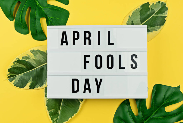 April Fool's day and tropical leaves on yellow - Foto, imagen
