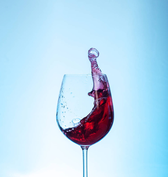 Pyszne czerwone wino w szklance na niebieskim tle. Koncepcja  - Zdjęcie, obraz