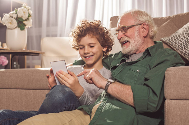 Cheerful granddad and boy watching at mobile - Фото, зображення