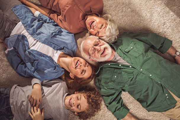 Laughing relatives locating on carpet - Photo, image