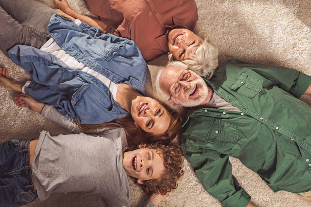 Laughing parents with boy locating on carpet - Photo, image