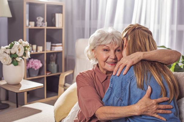 Glimlachend grootmoeder knuffelen meisje in kamer - Foto, afbeelding