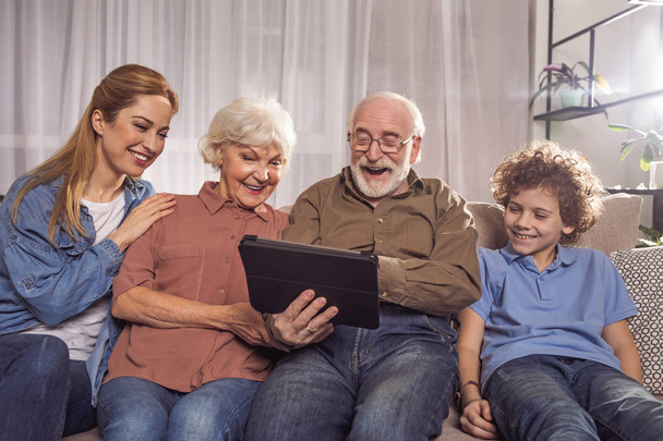 Glad relatives watching at digital device - Фото, изображение