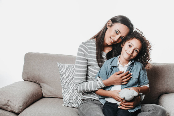 Smiling mom and child resting on sofa and hugging - Valokuva, kuva