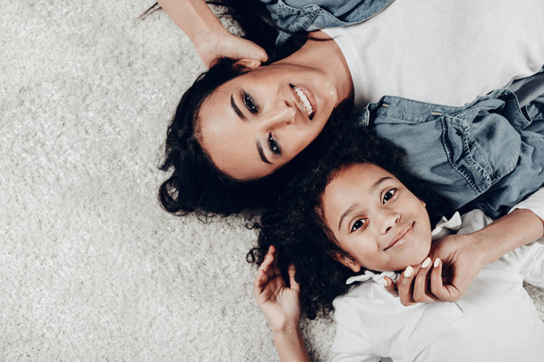 Cheerful mom and daughter resting on the floor - Foto, Imagen