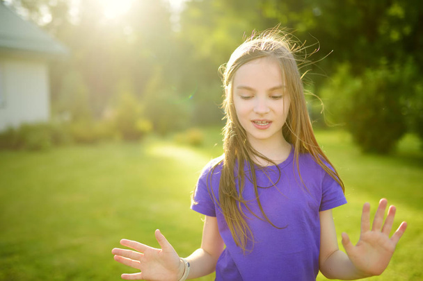 Söpö pikkutyttö pitää hauskaa nurmikolla takapihalla aurinkoisena kesäiltana. Kesätoimintaa lapsille
. - Valokuva, kuva