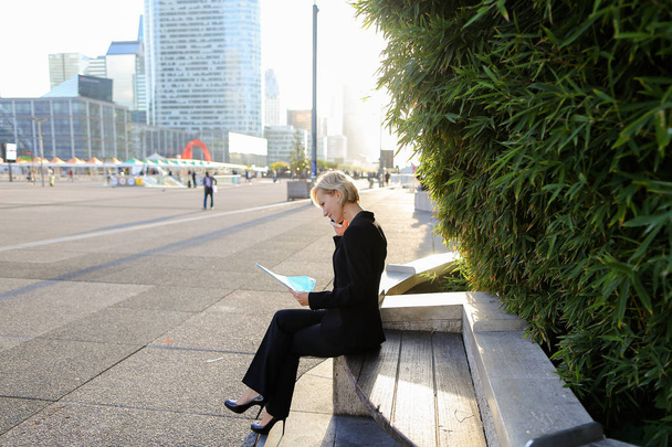Secretary talking by smartphone with document case in   outdoors - Foto, Bild