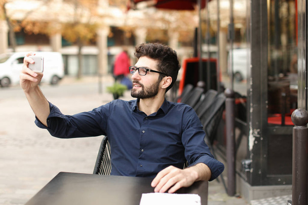 Estudiante escuchando música con smartphone y auriculares en la cafetería
 - Foto, Imagen
