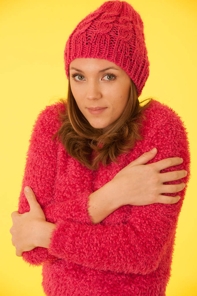 Portrait of a beautiful young woman in pink sweater over yellow background - Фото, зображення