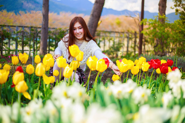 beautiful woman with tulips flowers in garden - Photo, Image