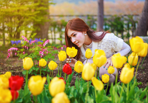 beautiful woman with tulips flowers in garden - Photo, Image