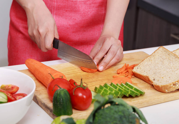 hand cutting carrot on board in kitchen room - Фото, зображення