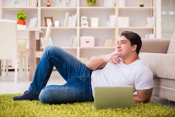 Man working on laptop at home on carpet floor - Zdjęcie, obraz