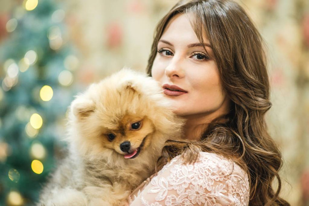 girl in dress with small dog at the Christmas tree - Φωτογραφία, εικόνα