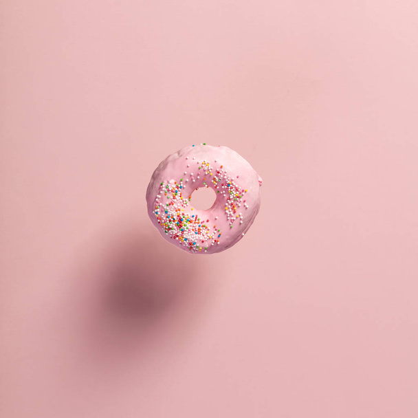 Pink doughnut with sprinkles falling or flying in motion - Foto, afbeelding