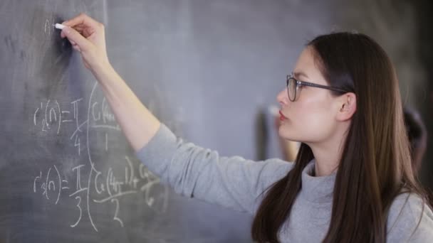 4K Young intelligent college student writing mathematical equation on blackboard - Záběry, video