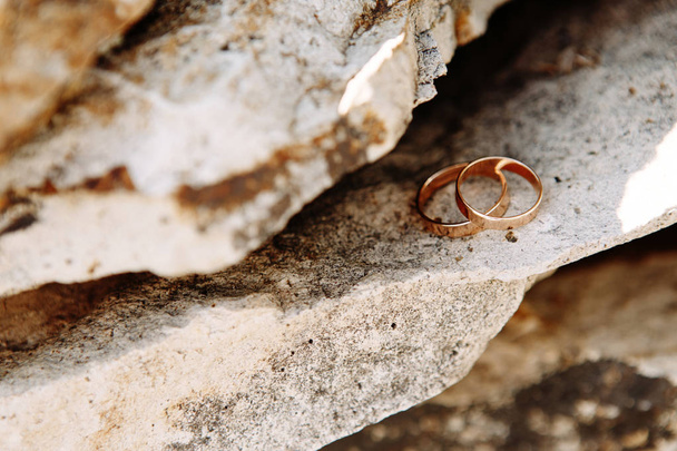 Primer plano de dos anillos de boda acostados en la roca
 - Foto, imagen