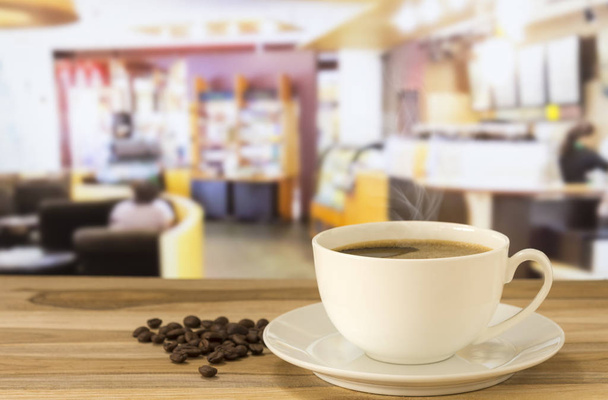 Кофейная чашка и кофейные зерна на столе в фоновом режиме кафе. Пространство для текста
. - Фото, изображение
