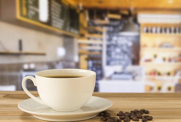 Kaffeetasse und Kaffeebohnen auf dem Tisch im Café Hintergrund. - Foto, Bild