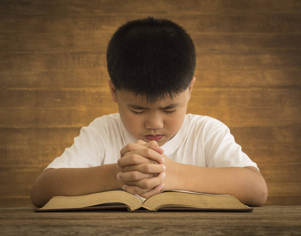 Мальчик положил руку на Библию, молись Богу
. - Фото, изображение
