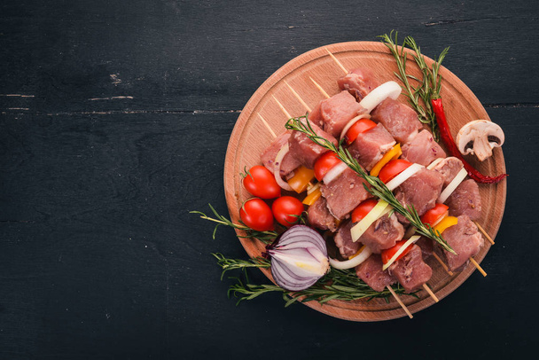 Raw kebab from meat on a wooden background with vegetables. Top view. Free space for text. - Fotoğraf, Görsel