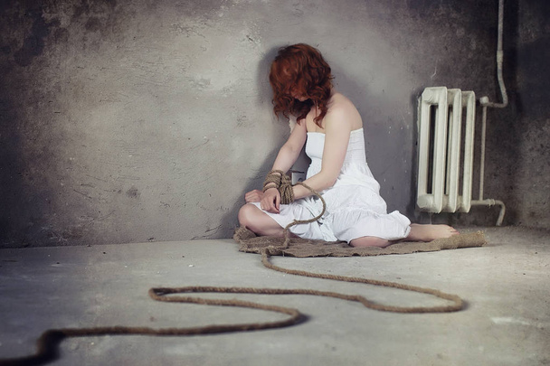 Fiatal lány kötve a padlón. Az elrabolt lány. Az áldozat o - Fotó, kép