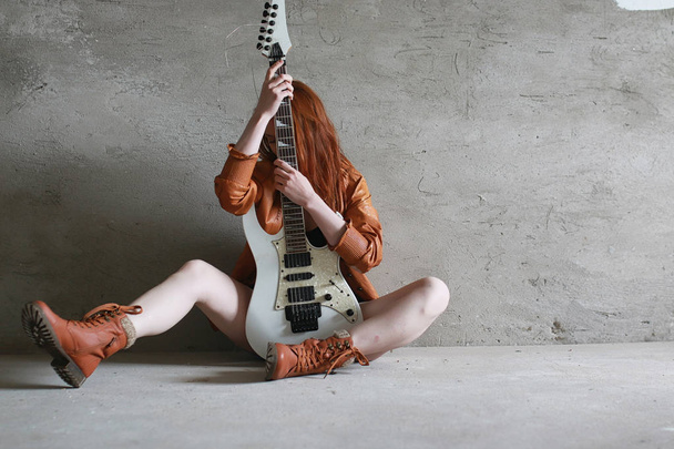 Молодая рыжая девушка с электрогитарой. Рок-музыкант
 - Фото, изображение