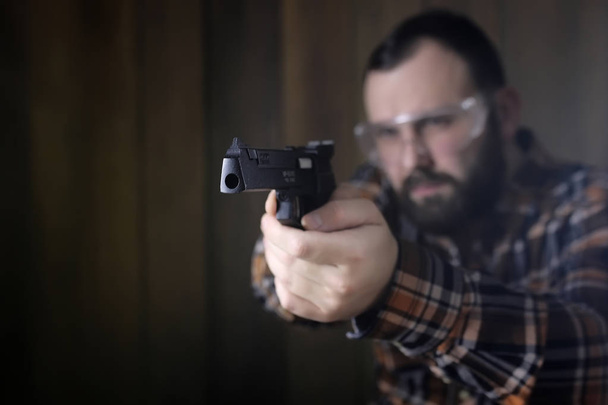 людина з одягненими захисними окулярами і навчанням вуха в пістолеті ш
 - Фото, зображення