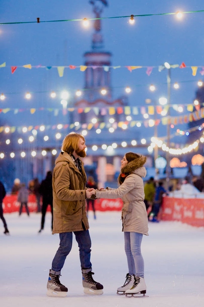 Patinoire à thème et couple aimant. rencontrer des jeunes gens élégants rouler à la main dans la foule sur la patinoire de la ville éclairée par des ampoules et des lumières. Patinage sur glace en hiver pour Noël sur glace
 - Photo, image