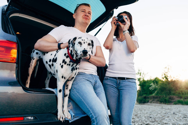 Retrato de feliz casal de jovens adultos com cão em viagem. Homem s
 - Foto, Imagem