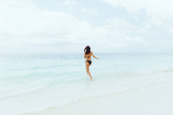 jeune femme courant dans l'océan à la journée ensoleillée, concept de vacances d'été
 - Photo, image