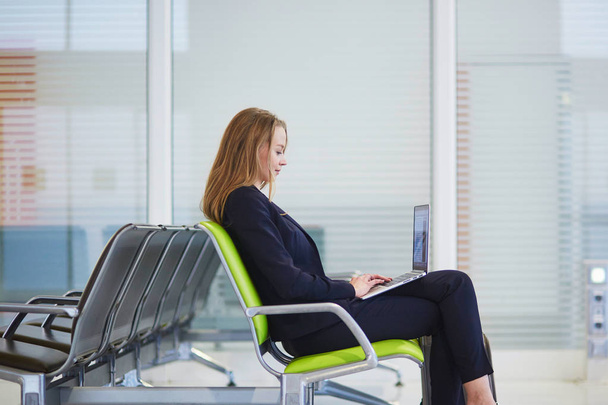 Giovane donna in aeroporto internazionale che lavora sul computer portatile in attesa del suo volo
 - Foto, immagini