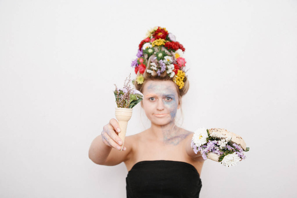 Egy fiatal nő, virágokkal a fejét és a kezét. Tavaszi kép virágokkal. A lány és a virágzó haircut és brokát arcán. - Fotó, kép