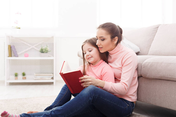 小さな女の子と彼女のお母さんは、家で本を読んで - 写真・画像