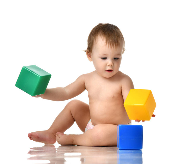 Infant child baby girl toddler playing holding green blue yellow bricks toys  - Zdjęcie, obraz