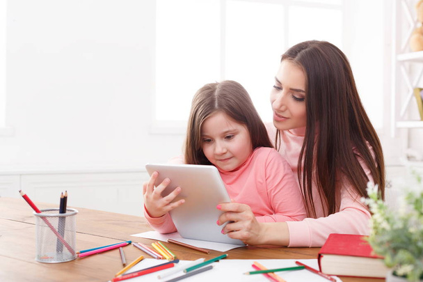 Μικρό κορίτσι και τη μάνα, χρησιμοποιώντας ένα tablet στο σπίτι - Φωτογραφία, εικόνα