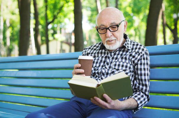 Elderly man in casual reading outdoors - Fotó, kép