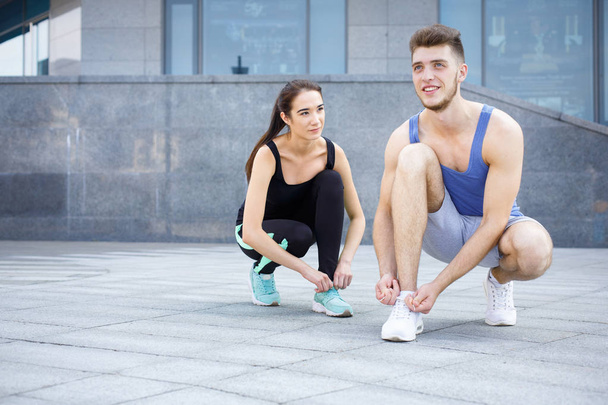Happy man and woman tying shoelaces before running - Photo, Image