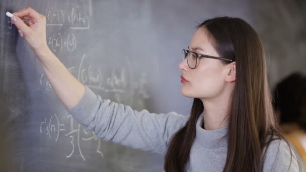 4K Young intelligent college student writing mathematical equation on blackboard - Filmati, video