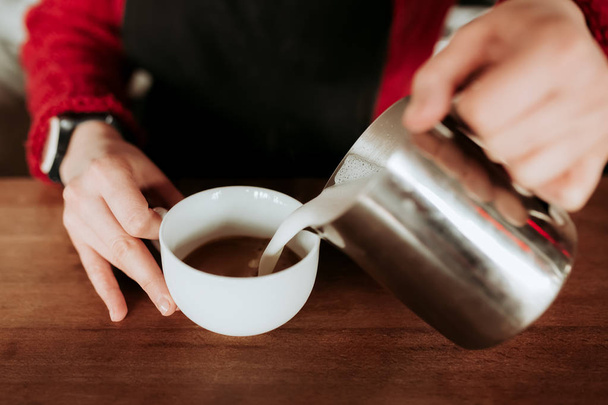 Barista is prepare making hot coffee cappuccino foam in white glass cup - Photo, image