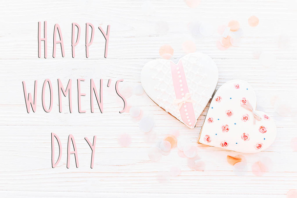 happy women's day text sign flat lay. 8 march. pink hearts and confetti on white rustic wooden background. space for text. greeting card concept. womens bright image - 写真・画像