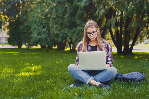 Serious young woman using laptop in park - Photo, Image
