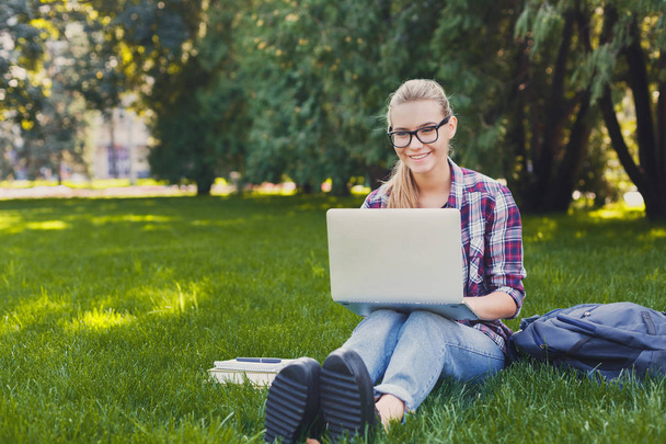 Happy young woman using laptop in park - Foto, Imagen